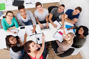 High angle view of university students doing group study at desk in classroom